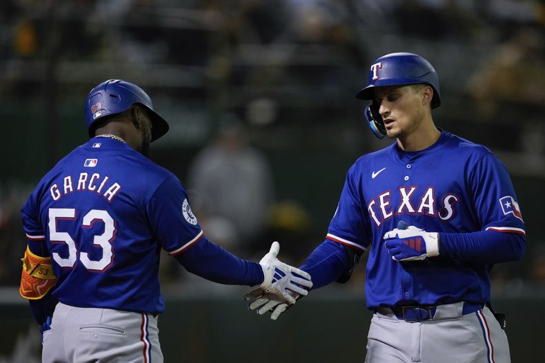 El campocorto de los Rangers de Texas Corey Seager (derecha) celebra junto al cubano Adolis García (53) luego de conectar un jonrón de tres carreras ante los Atléticos de Oakland durante el octavo episodio del juego de béisbol, el lunes 6 de mayo de 2024, en Oakland, California. (AP Foto/Godofredo A. Vásquez)