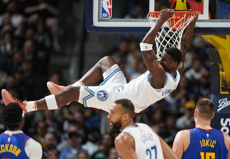 Anthony Edwards, de los Timberwolves de Minnesota, se cuelga del aro después de clavar un balón durante la primera mitad del juego de baloncesto de la NBA en contra de los Nuggets de Denver el viernes 29 de marzo de 2024, en Denver. (AP Foto/David Zalubowski)
