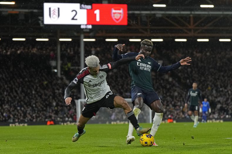 Antonee Robinson del Fulham pelea por el balón con Bukayo Saka del Arsenal en el encuentro de la Liga Premier en el Estadio Craven Cottage el domingo 31 de diciembre del 2023. (AP Foto/Alastair Grant)
