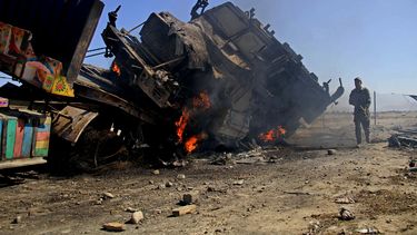 americateve | Un polic&iacute;a afgano observa un cami&oacute;n que cargaba provisiones de la OTAN en el distrito de Behsud, en la ciudad de Jalalabad, Afganist&aacute;n, el lunes 9 de junio de 2014. Atacantes suicidas atentaron contra un estacionamiento y una comisar&
