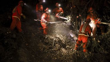 Un equipo de trabajo del Departamento de Correccionales de California trabaja en las líneas de contención para combatir el incendio Palisades el martes 14 de enero de 2025 en Santa Monica, California. (AP Foto/Ethan Swope)