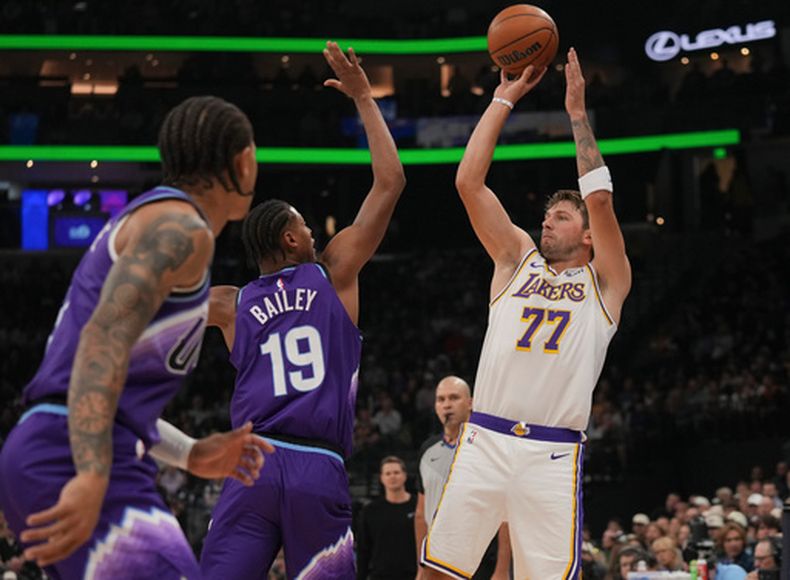El delantero y guardia de los Lakers de Los Ángeles, Luka Dončić (77), busca hacer un tiro mientras lo defiende el delantero del Jazz de Utah, Ace Bailey (19), durante la primera mitad de un partido de básquetbol de la NBA, el domingo 25 de octubre de 2026, en Salt Lake City. (Foto AP/Bethany Baker)