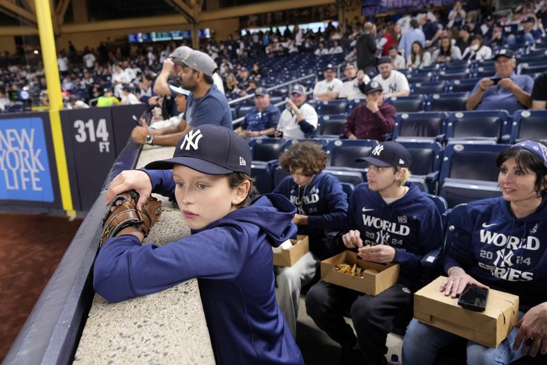 Everett Teel-Young, de 11 años, observa la práctica de bateo con su madre y hermanos previo al quinto juego de la Serie Mundial entre los Dodgers de Los Ángeles y los Yankees de Nueva York, el miércoles 30 de octubre de 2024, en Nueva York. (AP Foto/Seth Wenig)