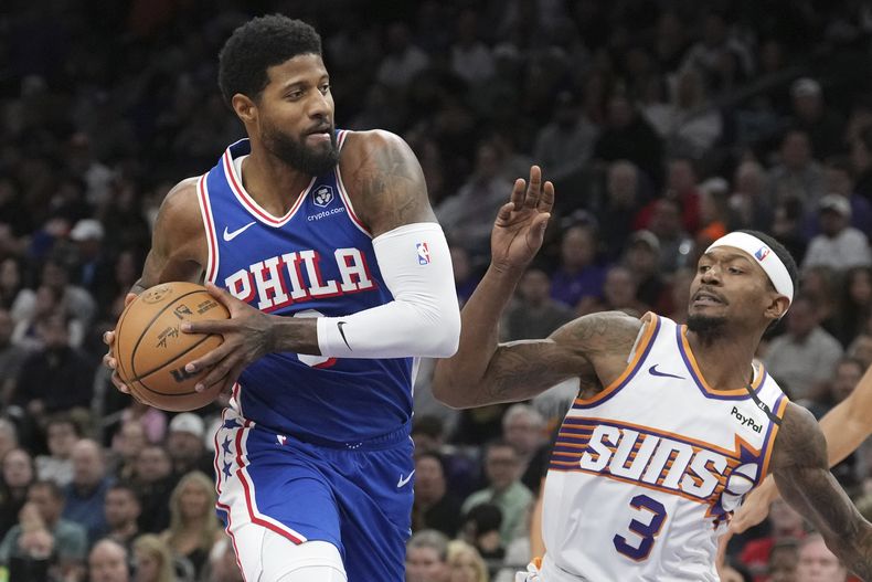 Paul George, de los 76ers de Filadelfia (izquierda), se dirige a canasta frente a su rival de los Suns Bradley Beal (3) en la primera mitad del partido de la NBA que enfrentó a ambos equipos, el 4 de noviembre de 2024, en Phoenix. (AP Foto/Ross D. Franklin)