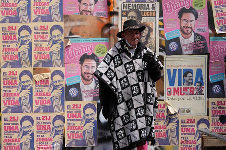 Un hombre fuma frente a carteles del candidato presidencial de la coalición Pacto Histórico, Iván Cepeda, en Bogotá, Colombia, el viernes 19 de junio de 2026. (AP Foto/Fernando Vergara)