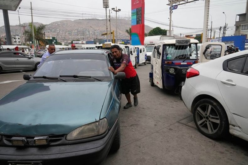 Un hombre empuja su auto en una fila de automovilistas que esperan para comprar gasolina después de que las autoridades la racionaran debido a una rotura en un gasoducto principal que afecta el suministro de gas a Lima, Perú, el miércoles 11 de marzo de 2026. (Foto AP/Martín Mejía)