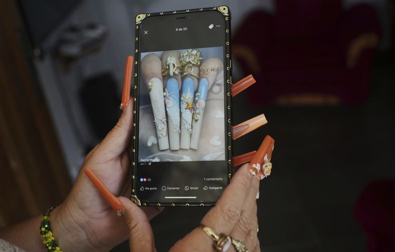Con sus largas y decoradas uñas, Miralys Maura Cruz muestra una imagen del tipo de diseño que le gusta en su vivienda en La Gallega, en la provincia de La Habana, Cuba, el sábado 28 de junio de 2025. (AP Foto/Ramon Espinosa)