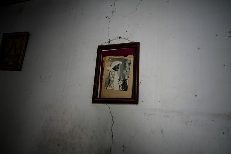 Una foto vieja de Regla Victoria Rodríguez cuelga de una pared agrietada en una desvencijada mansión en la que viven seis familias en la calle Villegas de La Habana, Cuba, el jueves 5 de octubre de 2023. El edificio de dos pisos, que alberga a seis familias, fue alguna vez una lujosa casa que colapsó parcialmente en los últimos años con evidentes daños. (AP Foto/Ramón Espinosa)