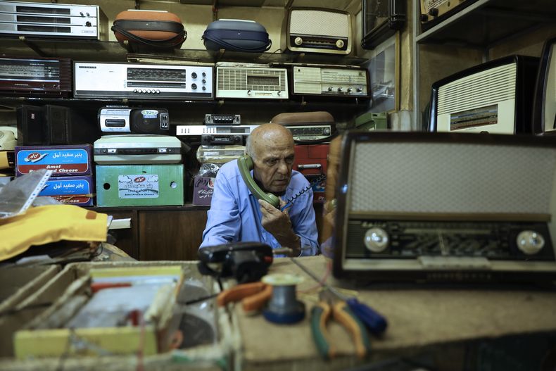Reza Alimirzaei, de 73 años, que repara y vende radios viejas, trabaja en su tienda en el centro de Teherán, Irán, el miércoles 18 de septiembre de 2024. (Foto AP/Vahid Salemi)