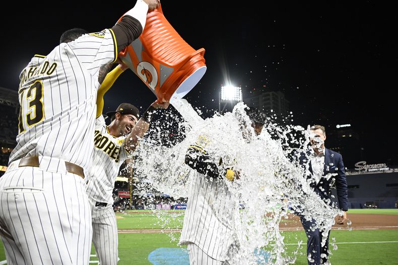 El tercera base Manny Machado y Tyler Wade de los Padres de San Diego vierten agua sobre Donovan solano tras su sencillo para la victoria en la décima ante los Dodgers de Los Ángeles el martes 30 de julio del 2024. (AP Foto/Denis Poroy)
