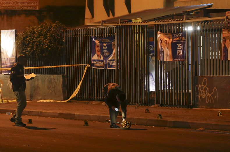 Investigadores de la policía caminan sobre la escena a las afueras del colegio en donde el candidato presidencial Fernando Villavicencio fue asesinado a tiros a la salida de un mítin electoral en un colegio en Quito, Ecuador, el miércoles 9 de agosto de 2023. (AP Foto/Juan Diego Montenegro)