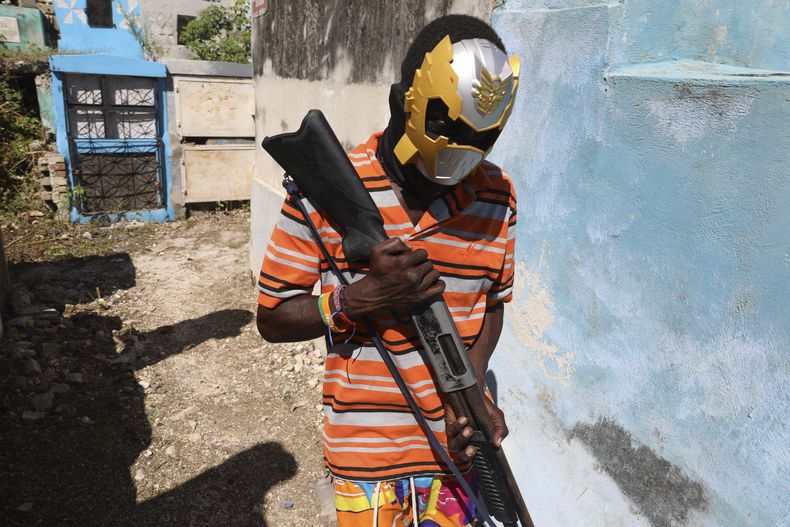 Un miembro de una banda, con el rostro cubierto por una máscara, posa para una foto en el Cementerio Nacional durante la conmemoración del Día de los Muertos en honor a los espíritus del vudú haitiano Baron Samedi y Gede, en Puerto Príncipe, Haití, el 1 de noviembre de 2024. (AP Foto/Odelyn Joseph)