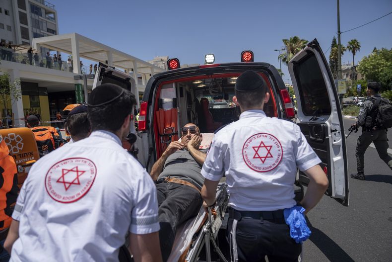 Paramédicos israelíes evacúan a un hombre herido en el lugar de un atropello deliberado palestino en una parada de autobús en Tel Aviv, Israel, el martes 4 de julio de 2023. (AP Foto/Oded Balilty)
