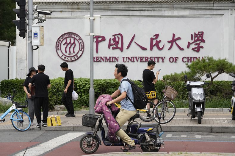 Gente pasa ante el logo de la Universidad de Renmin ante su principal campus en Beijing, el lunes 22 de julio de 2024. (AP Foto/Ng Han Guan)
