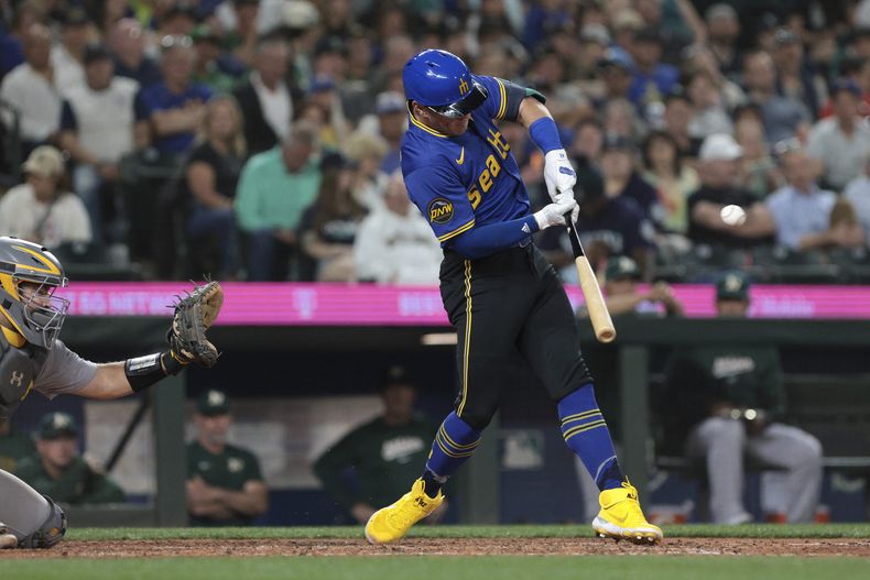 Dylan Moore, de los Marineros de Seattle, pega un sencillo en el encuentro del viernes 10 de mayo de 2024, ante los Atléticos de Oakland (AP Foto/Jason Redmond)