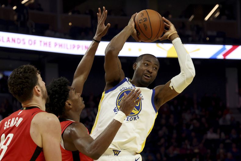 El alero de los Warriors de Golden State, Jonathan Kuminga (00), es defendido por el alero de los Rockets de Houston, Amen Thompson, durante la primera mitad de un partido de baloncesto de la NBA en San Francisco, el jueves 5 de diciembre de 2024. (AP Foto/Jed Jacobsohn)