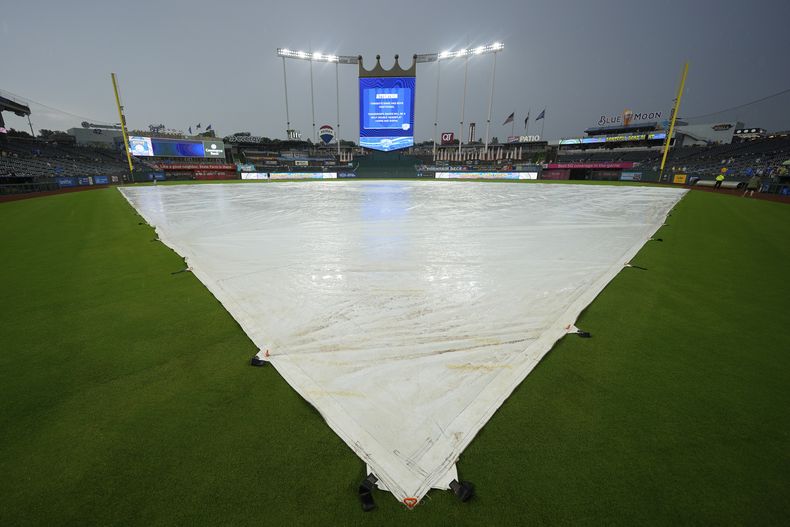 Una lona cubre el infield después de que un partido de béisbol entre los Guardianes de Cleveland y los Reales de Kansas City se pospusiera debido a la lluvia el viernes 25 de julio de 2025 en Kansas City, Missouri. (Foto AP/Charlie Riedel)
