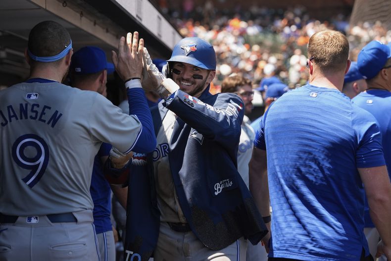 Spencer Horwitz (centro) festeja con Danny Jansen, su compañero en los Azulejos de Toronto, luego de sacudir un jonrón ante los Gigantes de San Francisco, el jueves 11 de julio de 2024 (AP Foto/Godofredo A. Vásquez)