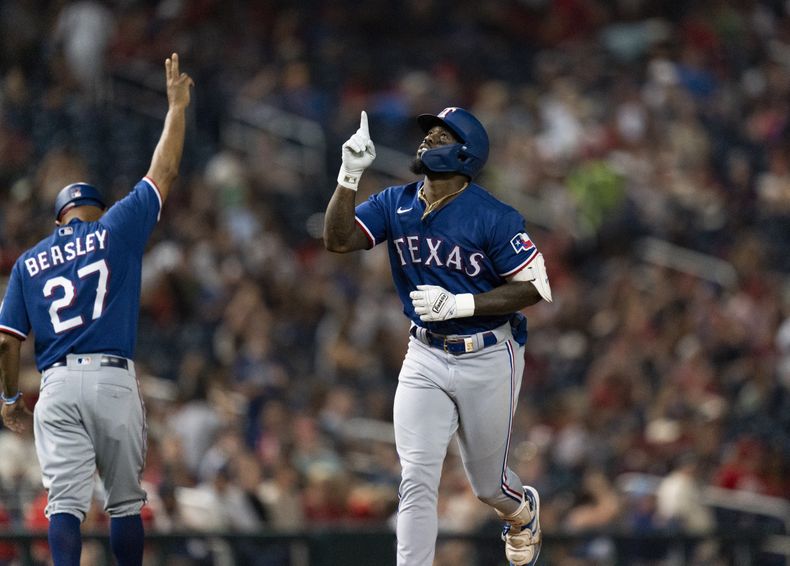 el jardinero derecho de los Rangers de Texas Adolis García celebra con el entrenador de tercera base Tony Beasley tras pegar un jonrón en la séptima entrada ante los Nacionales de Washington el viernes 7 de julio del 2023. (AP Foto/Stephanie Scarbrough)