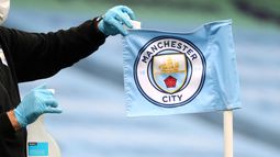 ARCHIVO - Foto del 22 de junio del 2020, trabajadores de campo ponen desinfectante en la bandera del Manchester City, equipo de la Liga Premier. (AP Foto/Martin Rickett,Pool, Archivo)