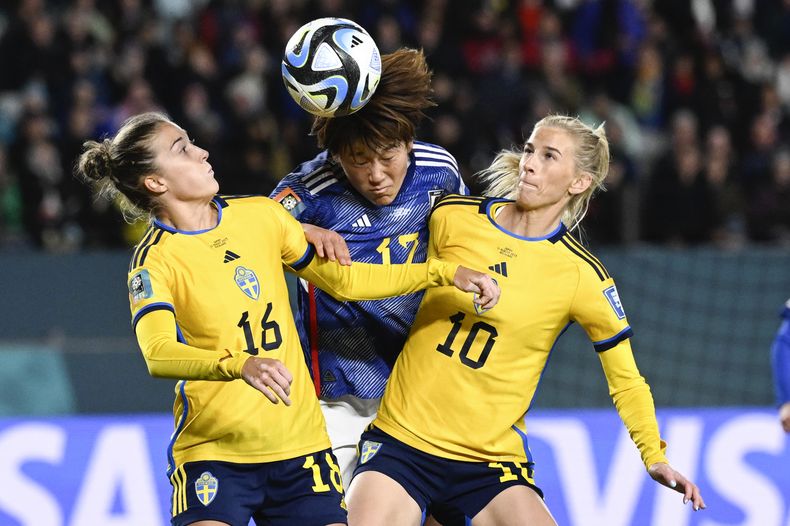 La japonesa Hana Takahashi (centro) intenta cabecear la pelota entre las suecas Filippa Angeldal (izquierda) y Sofia Jakobsson (derecha), en el partido de cuartos de final del Mundial femenino que enfrentó a ambos equipos en Auckland, Nueva Zelanda, el 11 de agosto de 2023. (AP Foto/Andrew Cornaga)