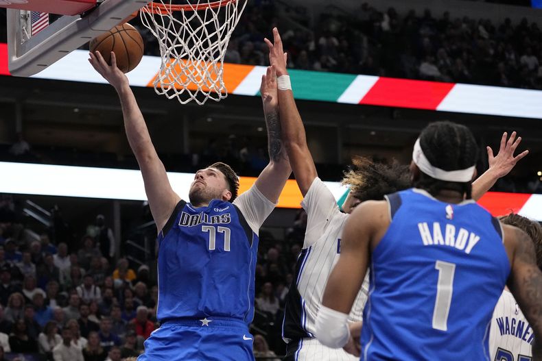 Luka Doncic (77), de los Mavericks de Dallas, supera la marca defensiva de Anthony Black, del Magic de Orlando, para encestar durante la primera mitad del juego de baloncesto de la NBA, en Dallas, el lunes 29 de enero de 2024. (AP Foto/Tony Gutierrez)