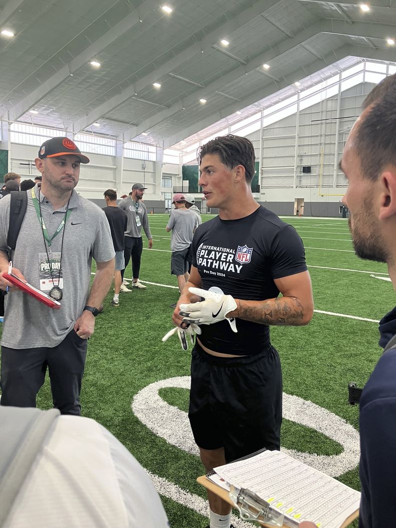 La estrella galesa del rugby Louis Rees-Zammit, en el centro, habla con los cazatalentos de la NFL después del Pro Day de la NFL para jugadores internacionales de la NFL, celebrado en la Universidad del Sur de Florida el miércoles 20 de marzo de 2024, en Tampa, Florida (AP Foto/Rob Maaddi)