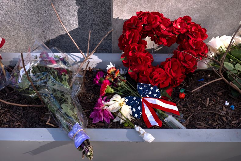 Un pequeño monumento hecho con banderas, flores y otros objetos en una jardinera, el viernes 28 de noviembre de 2025, cerca del sitio donde dos miembros de la Guardia Nacional fueron tiroteados en Washington. (AP Foto/Mark Schiefelbein)
