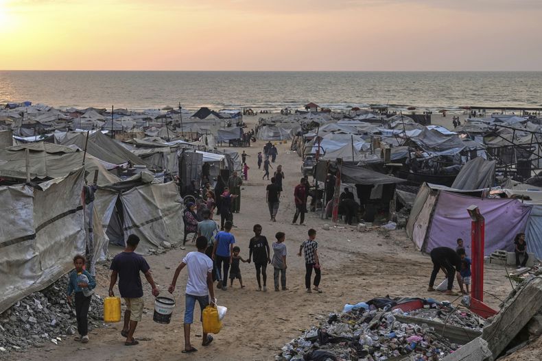 Palestinos desplazados caminan por un campamento improvisado en la playa de Ciudad de Gaza, el domingo 10 de agosto de 2025. (AP Foto/Jehad Alshrafi)