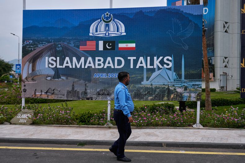 Un policía camina frente a una valla publicitaria sobre las negociaciones entre Estados Unidos e Irán en un centro de convenciones, el sábado 11 de abril de 2026, en Islamabad. (AP Foto/Anjum Naveed)