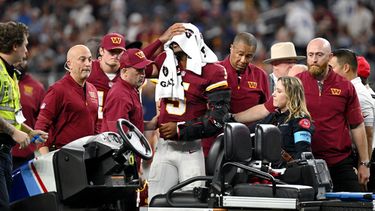 Los entrenadores atienden al quarterback de los Commanders de Washington, Jayden Daniels (5), tras una aparente lesión en la primera mitad contra los Cowboys de Dallas durante un partido de fútbol americano de la NFL en Arlington, Texas, el domingo 20 de septiembre de 2026. (Foto AP/Jessica Tobias)