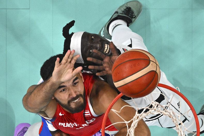 El puertorriquño Arnaldo Toro y el sudanés Wenyen Gabriel pugnan por el rebote en el partido por el baloncesto de los Juegos Olímpicos de París, el domingo 28 de julio de 2024, en Villeneuve-dAscq, France. (Sameer Al-Doumy/Pool Foto vía AP)