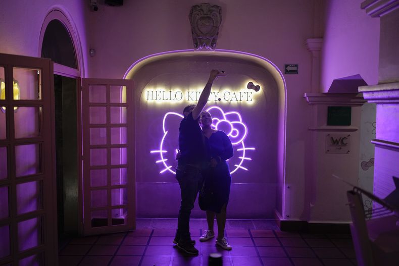 Fans del personaje japonés Hello Kitty se toman fotografías en un café con temática de Hello Kitty en la Ciudad de México, el jueves 10 de octubre de 2024. (Foto AP/Eduardo Verdugo)