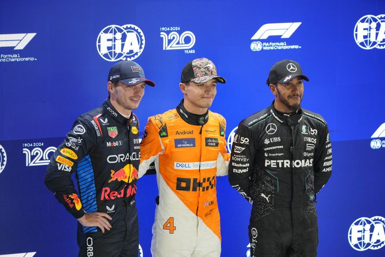 Lando Norris de McLaren celebra la pole junto a Max Verstappen de Red Bull, quien saldrá segundo y Lewis Hamilton de Mercedes, que saldrá tercero en el Gran Premio de Singapur el sábado 21 de septiembre del 2024. (AP Foto/Vincent Thian)