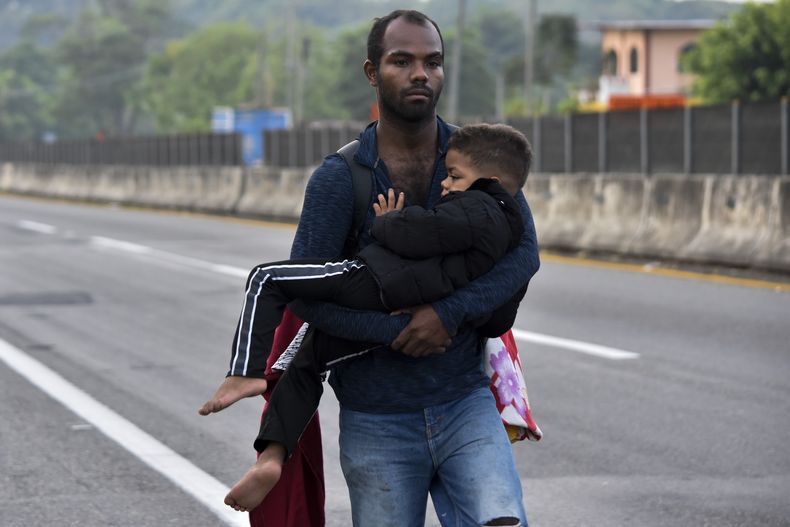 Un migrante carga a un niño por Tapachula, estado de Chiapas, México, el jueves 2 de enero de 2025, como parte de una caravana de migrantes que intentan llegar a la frontera con Estados Unidos. (AP Foto/Edgar H. Clemente)