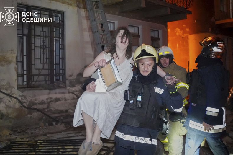 En esta imagen, distribuida por el Servicio de Emergencia de Ucrania, un bombero evacúa a una residente de un edificio en llamas tras un ataque aéreo ruso, en Odesa, Ucrania, el 20 de junio de 2025. (Servicio de Emergencia de Ucrania vía AP)
