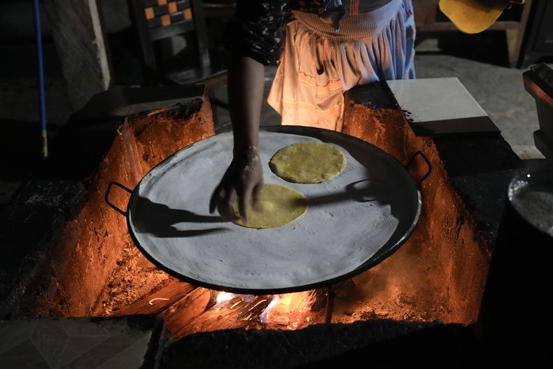 Una mujer joven prepara tortillas sobre el fuego en su cocina en Plan de Ayala, un pueblo tojolabal en la localidad de Las Margaritas del estado de Chiapas, México, el jueves 2 de mayo de 2024. Dos mujeres están en la papeleta para las elecciones presidenciales mientras en algunas áreas indígenas, las mujeres no tienen voz en sus propias comunidades. No obstante, con ayuda de las nuevas generaciones, algunas mujeres indígenas están empujando el cambio. (AP Foto/Marco Ugarte)