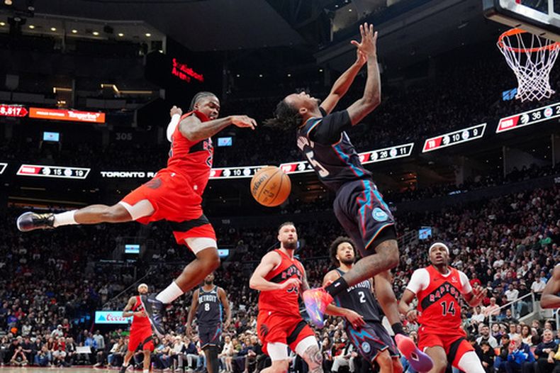 Jonathan Mogbo, izquierda, de los Raptors de Toronto, le arrebata el balón a Ronald Holland II (5), de los Pistons de Detroit, durante la segunda mitad del juego de baloncesto de la NBA, el domingo 15 de marzo de 2026, en Toronto. (Frank Gunn/The Canadian Press via AP)