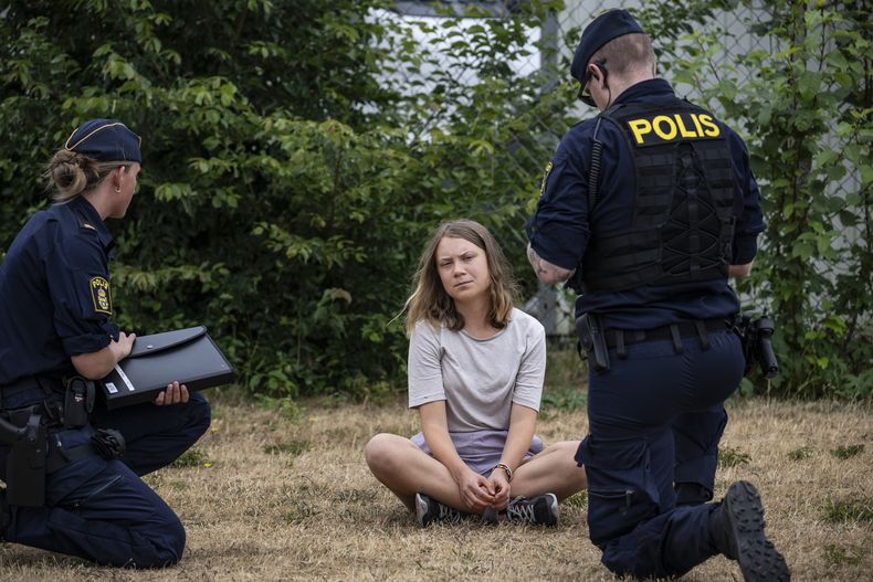 ARCHIVO - Agentes de la policía hablan con la activista climática sueca Greta Thunberg mientras retiran a otros activistas que bloqueaban la entrada de un vecindario de Malmö, Suecia, el lunes 19 de junio de 2023.(Johan Nilsson/TT News Agency via AP, Archivo)