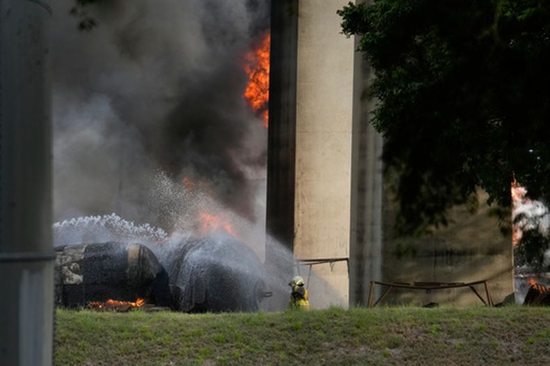 Un bombero rocía agua sobre camiones cisterna que se incendiaron después de que varios explotaran bajo el puente Las Américas, junto al Canal de Panamá, en la Ciudad de Panamá, el lunes 6 de abril de 2026. (AP Foto/Matías Delacroix)