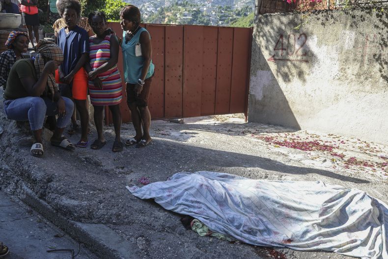 Los residentes se reúnen ante una persona que, según afirman, fue asesinada en un ataque perpetrado por miembros de una pandilla, en el barrio de Pétion-Ville de Puerto Príncipe, Haití, el martes 19 de noviembre de 2024. (Foto AP/Odelyn Joseph)