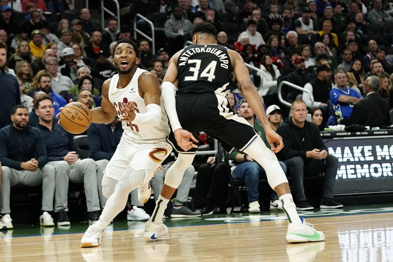 Donovan Mitchell de los Cavaliers de Cleveland (izquierda) conduce hacia el aro ante Giannis Antetokounmpo, de los Bucks de Milwaukee durante un partido del baloncesto de la NBA. (AP Foto/Aaron Gash)