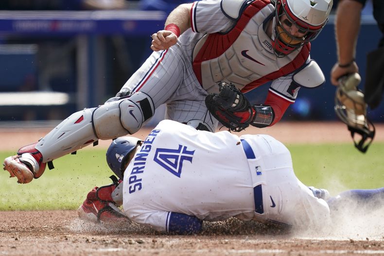George Springer, de los Azulejos de Toronto, choca con el cátcher Ryan Jeffers, de los Mellizos de Minnesota, en el juego del sábado 10 de junio de 2023 (Arlyn McAdorey/The Canadian Press via AP)