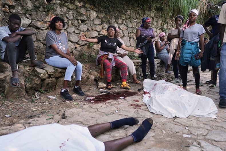 Varias personas se reúnen junto a los cuerpos de quienes, según dijeron, eran sus familiares y fueron asesinados en un ataque de pandillas en el barrio de Kenscoff, el lunes 24 de agosto de 2026, en Puerto Príncipe, Haití. (AP Foto/Odelyn Joseph)