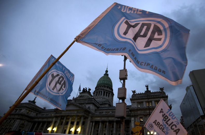 ARCHIVO - Partidarios de un proyecto de ley de nacionalización petrolera propuesto por la presidenta argentina Cristina Fernández ondean banderas con la leyenda Lucha y devuelve YPF, frente al Congreso en Buenos Aires, Argentina, el 25 de abril de 2012. (Foto AP/Natacha Pisarenko, Archivo)