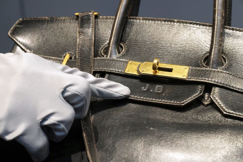 Un oficial de subasta señala las iniciales de Jane Birkin en el bolso Birkin original creado por Hermès para Jane Birkin en 1984, antes de su subasta el jueves 10 de julio de 2025 en París. (Foto AP/Michel Euler)