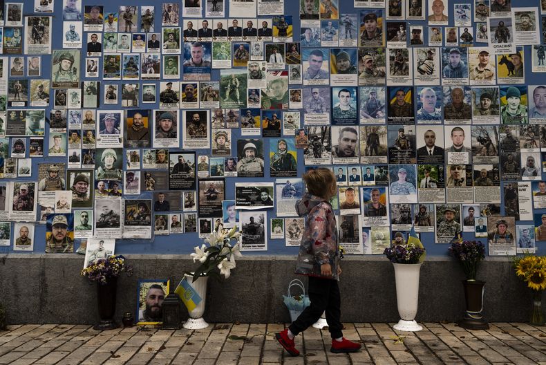 Una niña observa las fotografías de los soldados ucranianos muertos en la guerra contra Rusia, en el Muro del Recuerdo, en Kiev, Ucrania, el 27 de julio de 2023. (AP Foto/Jae C. Hong)