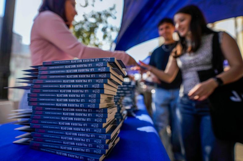 Ejemplares de La palabra maldita y otros escritos urgentes de Gabriela Mistral se apilan mientras la gente hace fila para obtener ejemplares gratuitos en el campus de la Universidad de Chile durante el Día Internacional del Libro, en Santiago de Chile, el jueves 23 de abril de 2026. (AP Foto/Esteban Felix)
