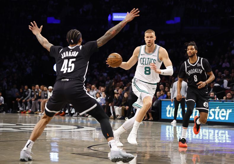 Kristaps Porzingis (8), de los Celtics de Boston, conduce hacia la canasta contra Keon Johnson (45) y Ziaire Williams (8), de los Nets de Brooklyn, durante la primera mitad de un partido de baloncesto de la NBA, el sábado 15 de marzo de 2025, en Nueva York. (AP Foto/Noah K. Murray)