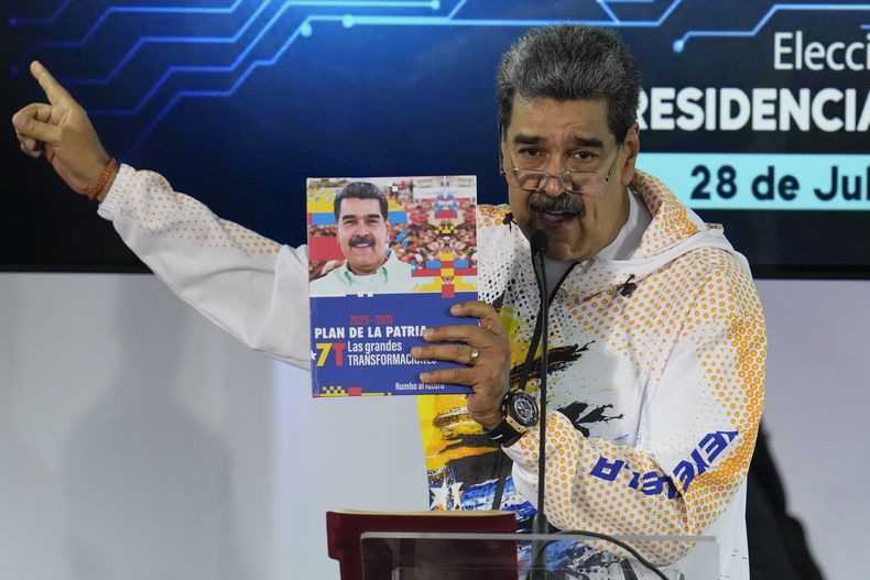 ARCHIVO - El presidente venezolano Nicolás Maduro sostiene un libro con su fotografía mientras habla en la Comisión Nacional Electoral, adonde llegó para formalizar su candidatura para postularse nuevamente a la presidencia en Caracas, Venezuela, el lunes 25 de marzo de 2024. Las elecciones están programadas para el 28 de julio. (AP Foto/Ariana Cubillos, Archivo)